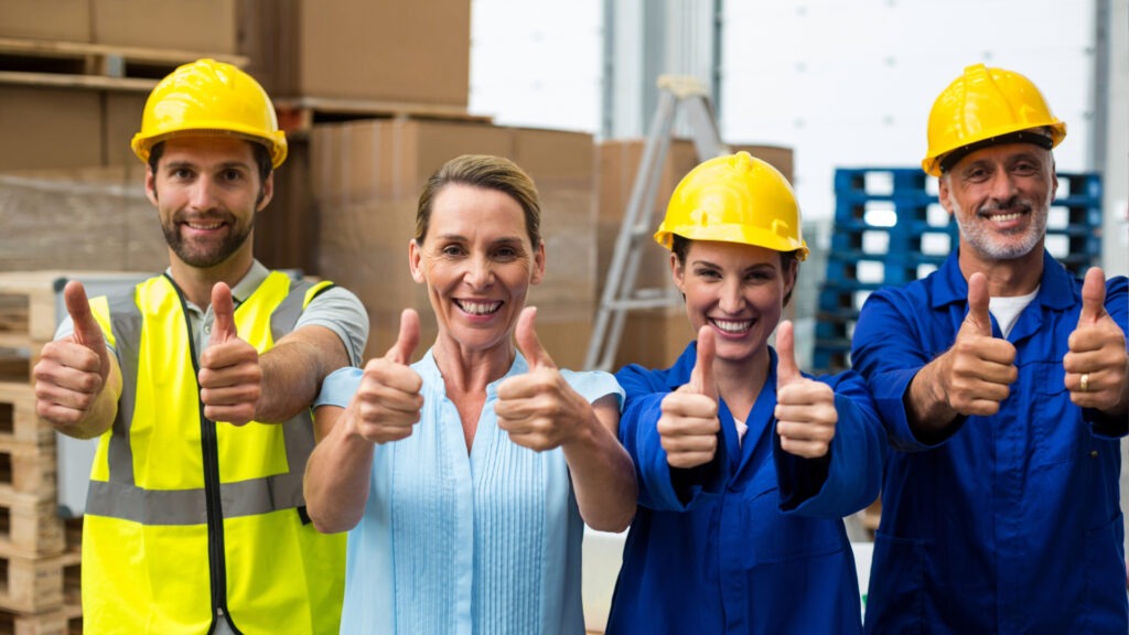 Group of smiling construction workers showing thumbs up 